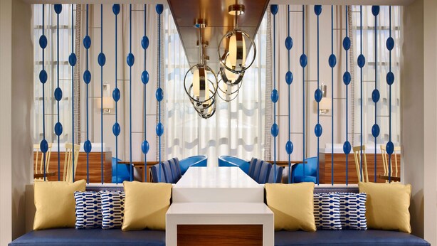 A modern living room with a blue sofa set, patterned cushions, and a central wooden coffee table. - Sonesta ES Suites Somerset (Somerset)