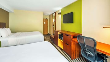 Ett hotellrum med en säng, ett skrivbord med en stol, en tv och en spegel.