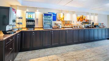 A hotel breakfast area with a self-service beverage station, a coffee machine, and a variety of food options.