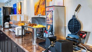 A buffet area with a waffle maker, a coffee machine, and various food items. - Comfort Inn Midland (Midland)