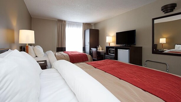 A hotel room with two beds, a TV, a desk, and a mirror. - Comfort Inn Midland (Midland)