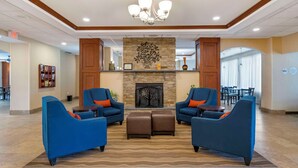 A spacious lobby with a fireplace, blue armchairs, and a chandelier. - Comfort Inn & Suites Watertown - 1000 Islands (Watertown)