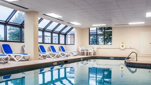 An indoor swimming pool with clear blue water, lounge chairs, and a sunbed area. - Comfort Inn & Suites Watertown - 1000 Islands (Watertown)