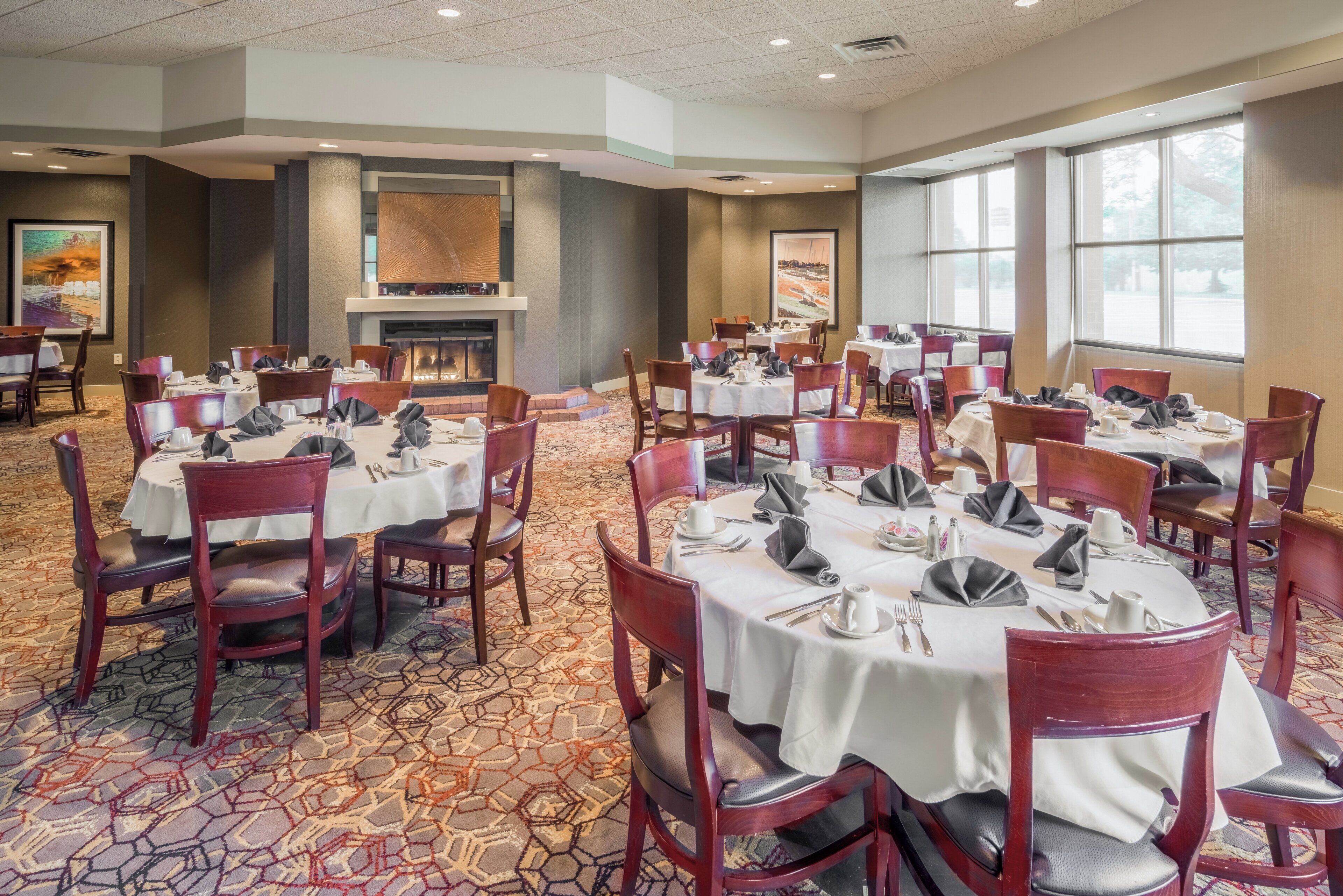 A conference room with round tables, chairs, and a fireplace.