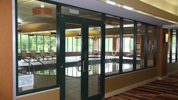 A hotel lobby with a glass door leading to a pool area.