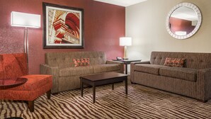 A living room with two couches, a coffee table, and a round mirror on the wall.