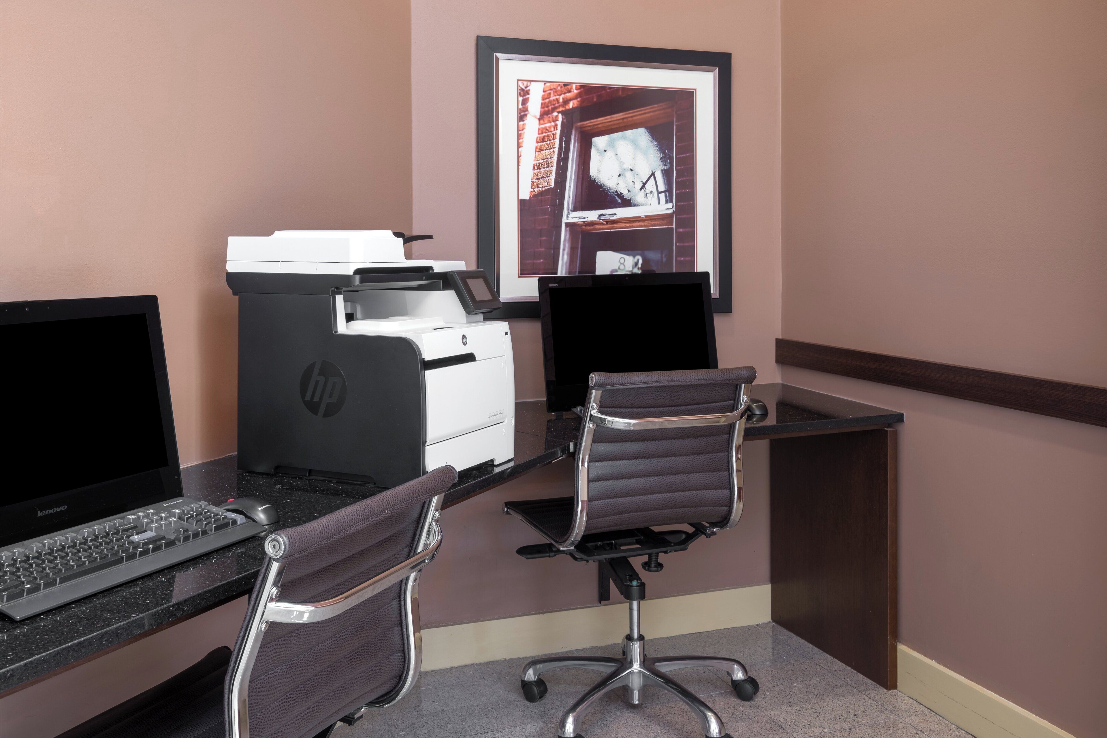 A workspace with a desktop computer, a printer, and a chair.