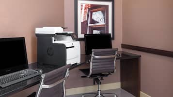 A workspace with a desktop computer, a printer, and a chair.