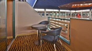 A modern hotel lobby with a high ceiling, a zebra-patterned carpet, and a glass partition with a view of the lobby area.