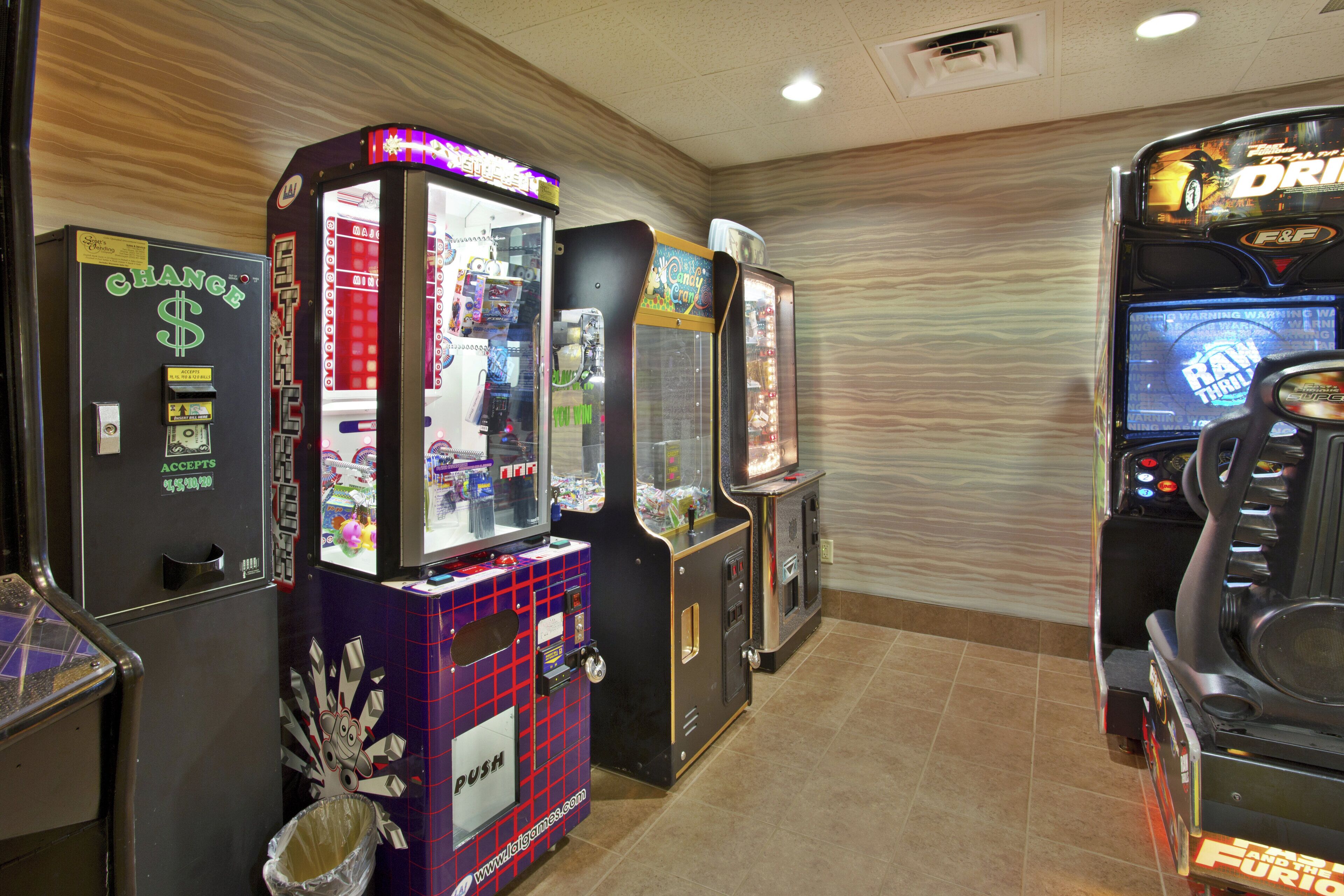 A row of arcade machines in a room with a tiled floor and a patterned wall.