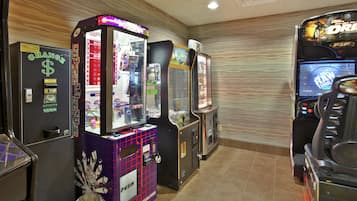 A row of arcade machines in a room with a tiled floor and a patterned wall.