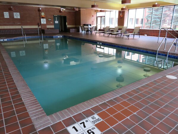 An indoor swimming pool with a tiled edge, lounge chairs, and a no diving sign.