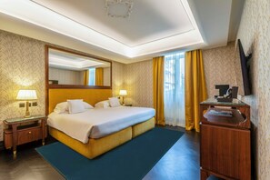 A hotel room with a large bed, a wooden nightstand with a lamp, a dresser, and a mirror.