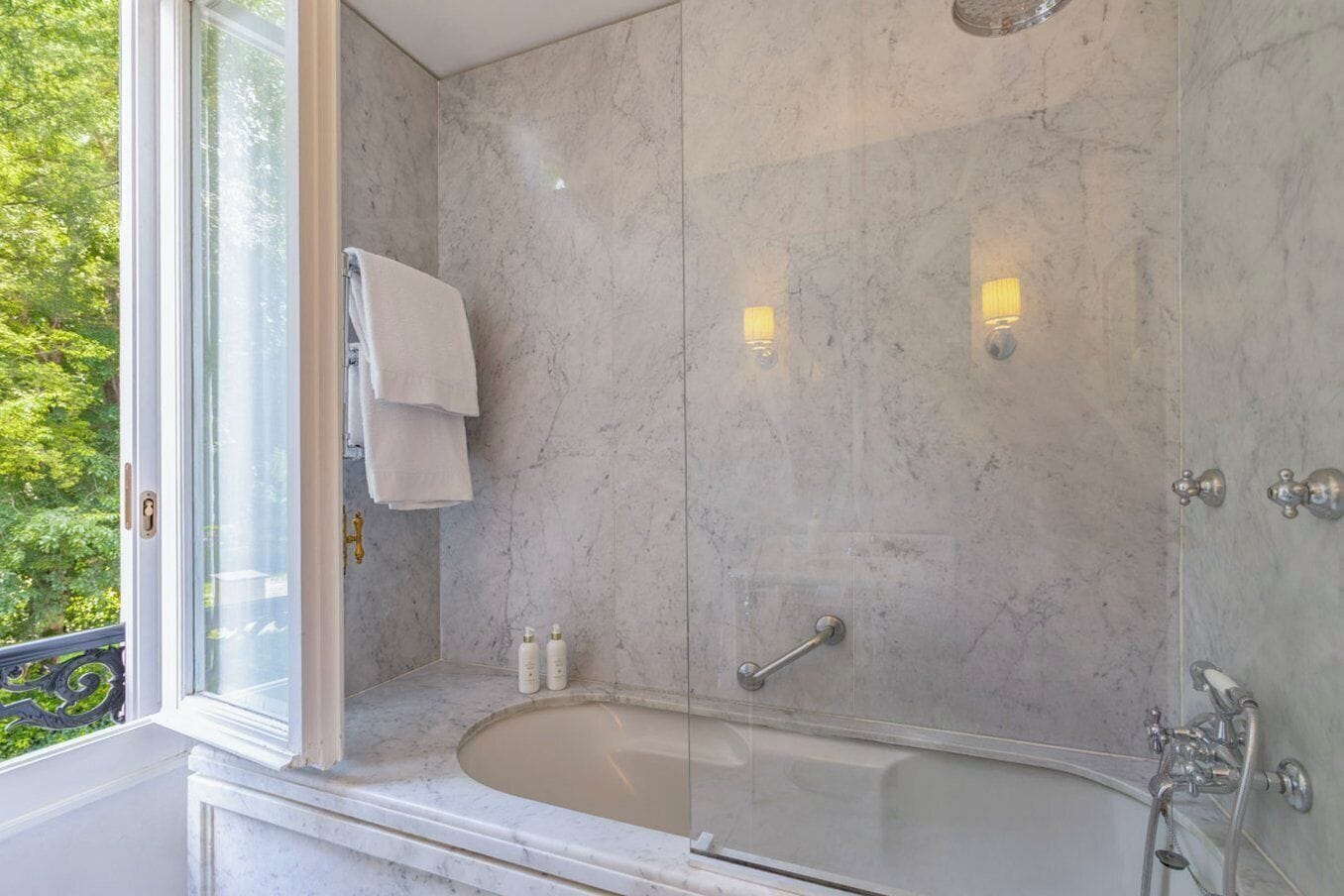 Un bagno moderno con doccia a vetro, vasca da bagno e finestra vista sul verde.