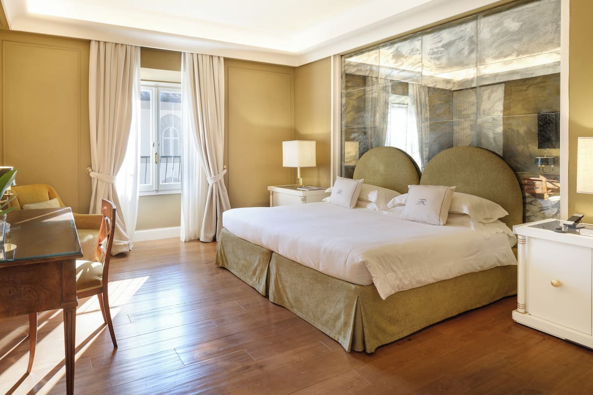 A hotel room with a large bed, a desk, and a chair.