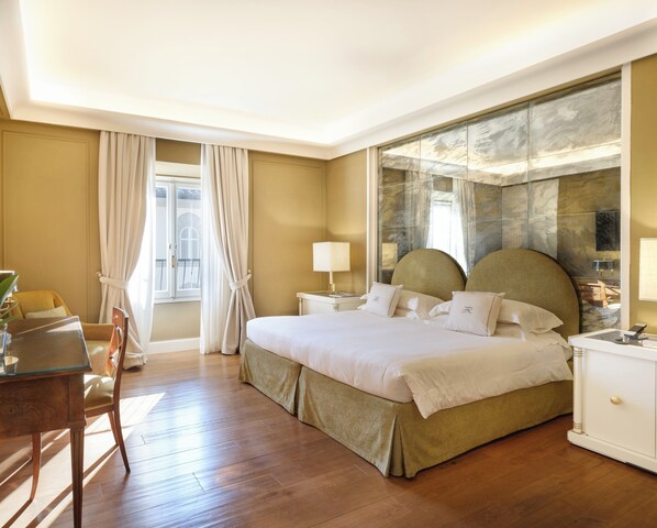 A hotel room with a large bed, a desk, and a chair.