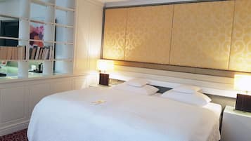 Habitación de hotel con una cama grande, dos lámparas de noche, un armario con espejo y un cabecero estampado.