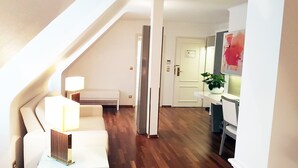 A modern apartment with a staircase, a white sofa, a desk with a lamp, and a potted plant. - Best Western Plus Hotel StadtPalais (Braunschweig)