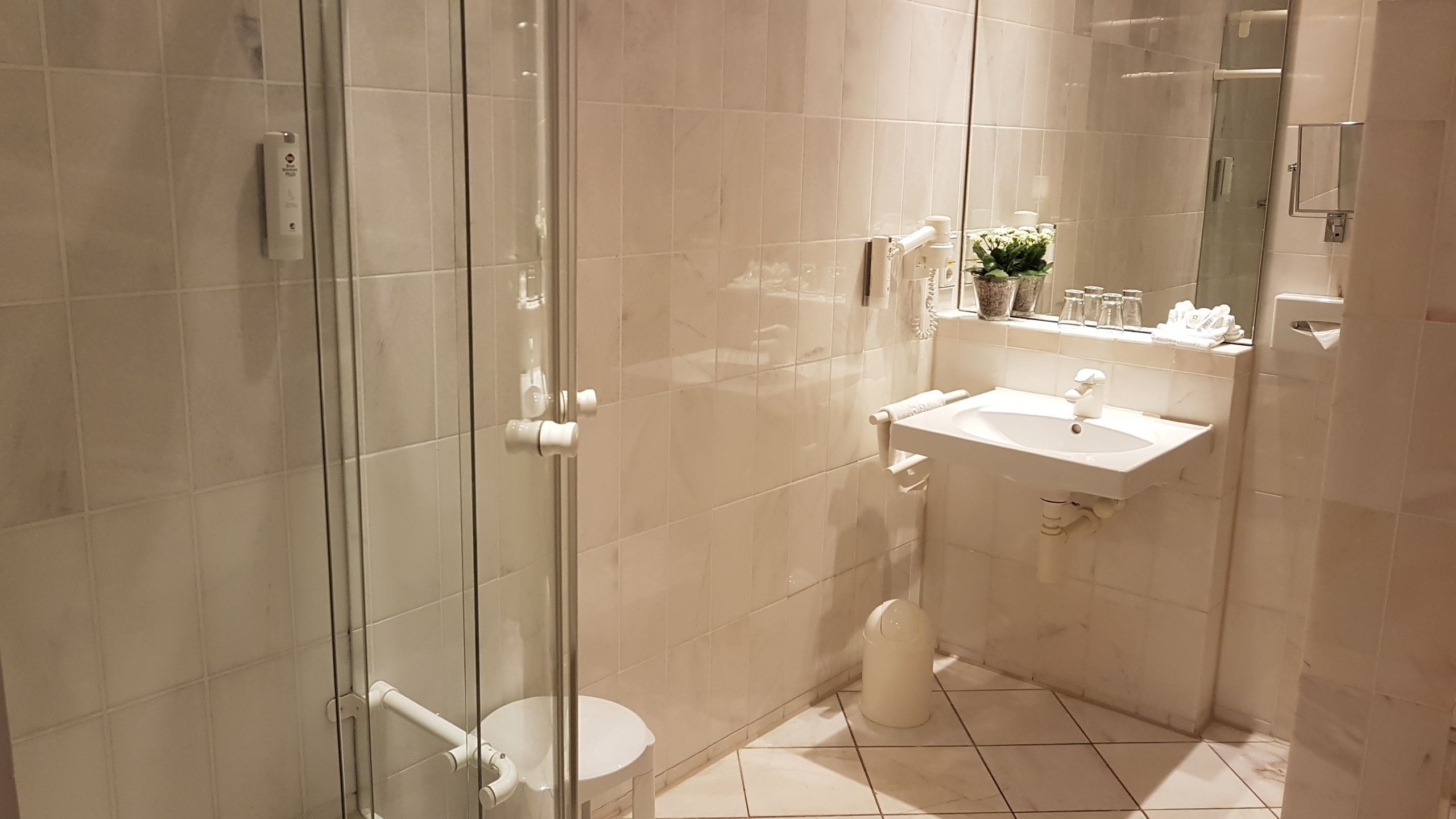 Un baño moderno con cabina de ducha de vidrio, un lavabo blanco y un espejo sobre el lavabo.