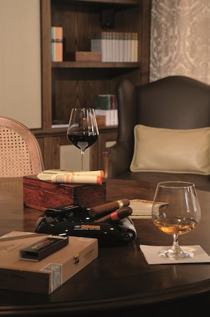 A wooden table with a glass of wine, a cigar, and a cigar box. - Best Western Plus Hotel StadtPalais (Braunschweig)