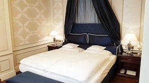 A neatly made bed with white linens, a dark blue canopy, and two bedside tables with lamps. - Best Western Plus Hotel StadtPalais (Braunschweig)
