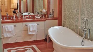 A luxurious bathroom with a large freestanding bathtub, a double vanity with a mirror, and a chandelier.