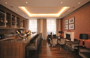 A bar area with a minibar, bar stools, and a large bowl of champagne bottles. - Best Western Plus Hotel StadtPalais (Braunschweig)