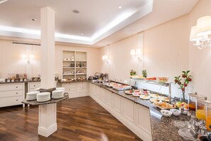 A hotel kitchen with a buffet setup, including a variety of food items and a juice bar. - Best Western Plus Hotel StadtPalais (Braunschweig)
