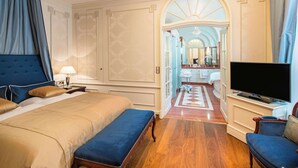 A hotel room with a large bed, a TV, a seating area, and a bathroom visible through an arched doorway. - Best Western Plus Hotel StadtPalais (Braunschweig)