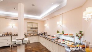A spacious hotel kitchen with a long counter, various food items, and a buffet setup. - Best Western Plus Hotel StadtPalais (Braunschweig)