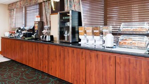 A hotel breakfast area with a wooden counter, coffee machines, and various food dispensers. - Baymont by Wyndham Clarksville Northeast (Clarksville)