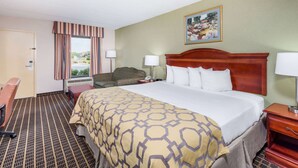 A hotel room with a large bed, a desk, a chair, and a window with curtains. - Baymont by Wyndham Clarksville Northeast (Clarksville)