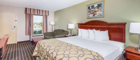 A hotel room with a large bed, a desk, a chair, and a window with curtains.