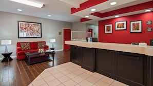 A hotel lobby with a reception desk, a red sofa, a coffee table, and a framed artwork on the wall. - Best Western Paris Inn (Paris)