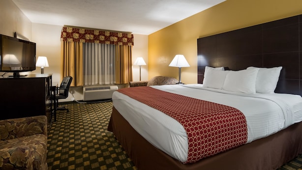 A hotel room with a large bed, a desk with a TV, a chair, and a sofa. - Best Western Paris Inn (Paris)