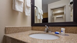 A bathroom with a granite countertop, a sink, a mirror, and a towel rack.
