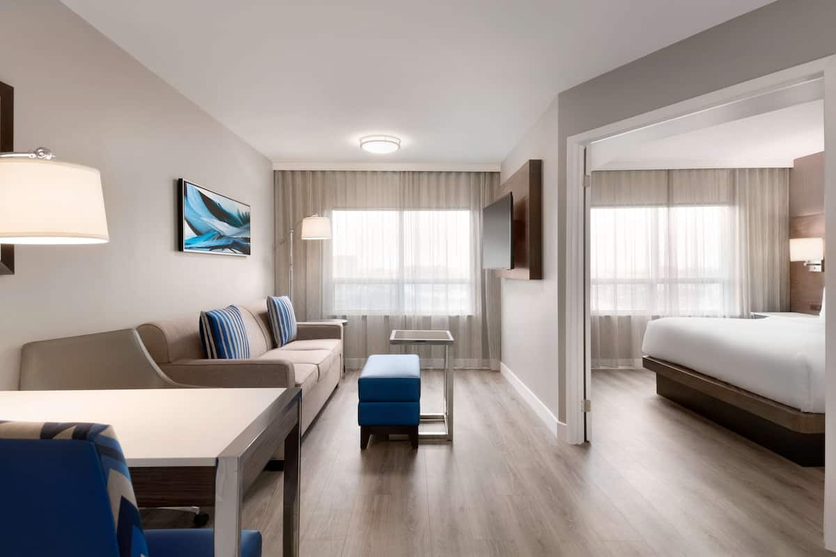 A hotel room with a bed, a sofa, a desk, a chair, and a small table.