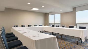 A conference room with a long table, chairs, and a carpeted floor.