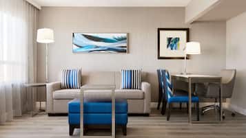 Habitació d'hotel moderna amb sofà, otomana, escriptori i cadira.