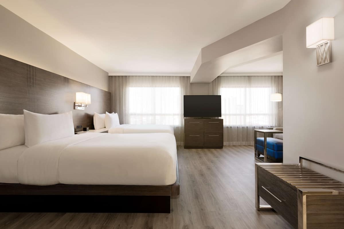 A hotel room with a large bed, a TV, a desk, and a chair.