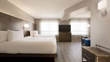 Una habitación de hotel con una cama grande, televisión, escritorio y una silla.