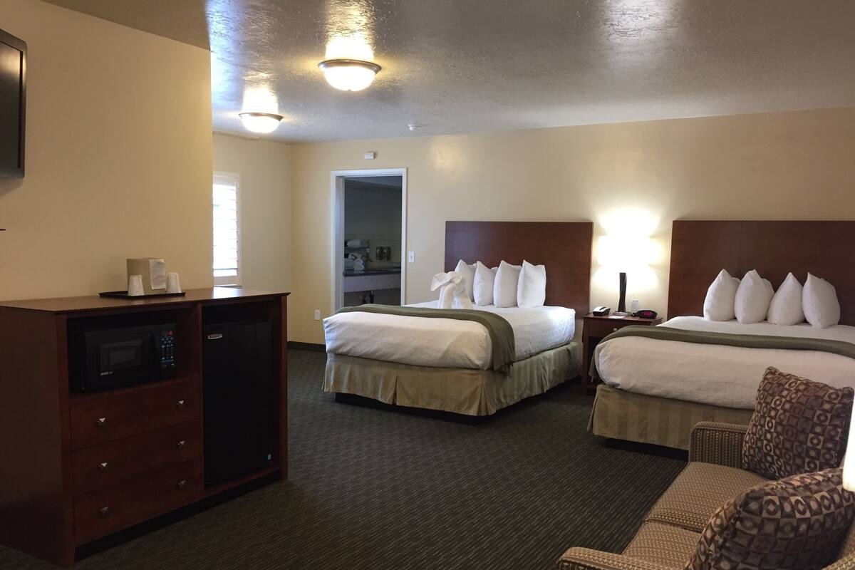 A hotel room with two beds, a microwave, a desk, and a chair.