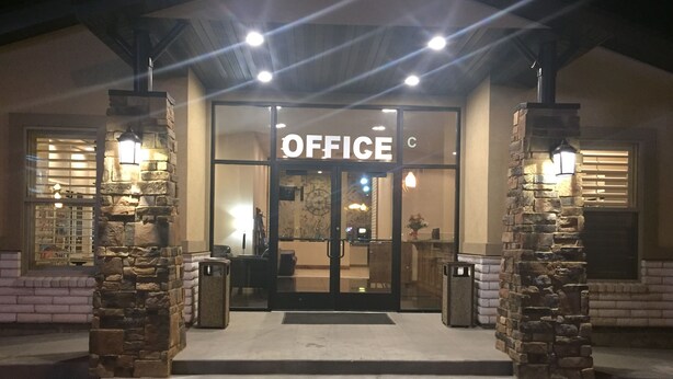 L’entrée d’un immeuble de bureaux, avec une porte en verre, des piliers en pierre et une enseigne indiquant « BUREAUX ».