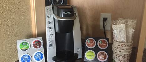A Keurig coffee maker with various coffee pods on a countertop.
