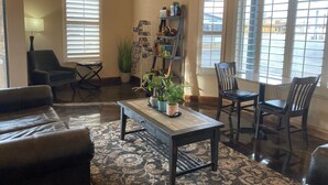 Un salon comprenant un canapé, des fauteuils, une table basse, une bibliothèque et un téléviseur.
