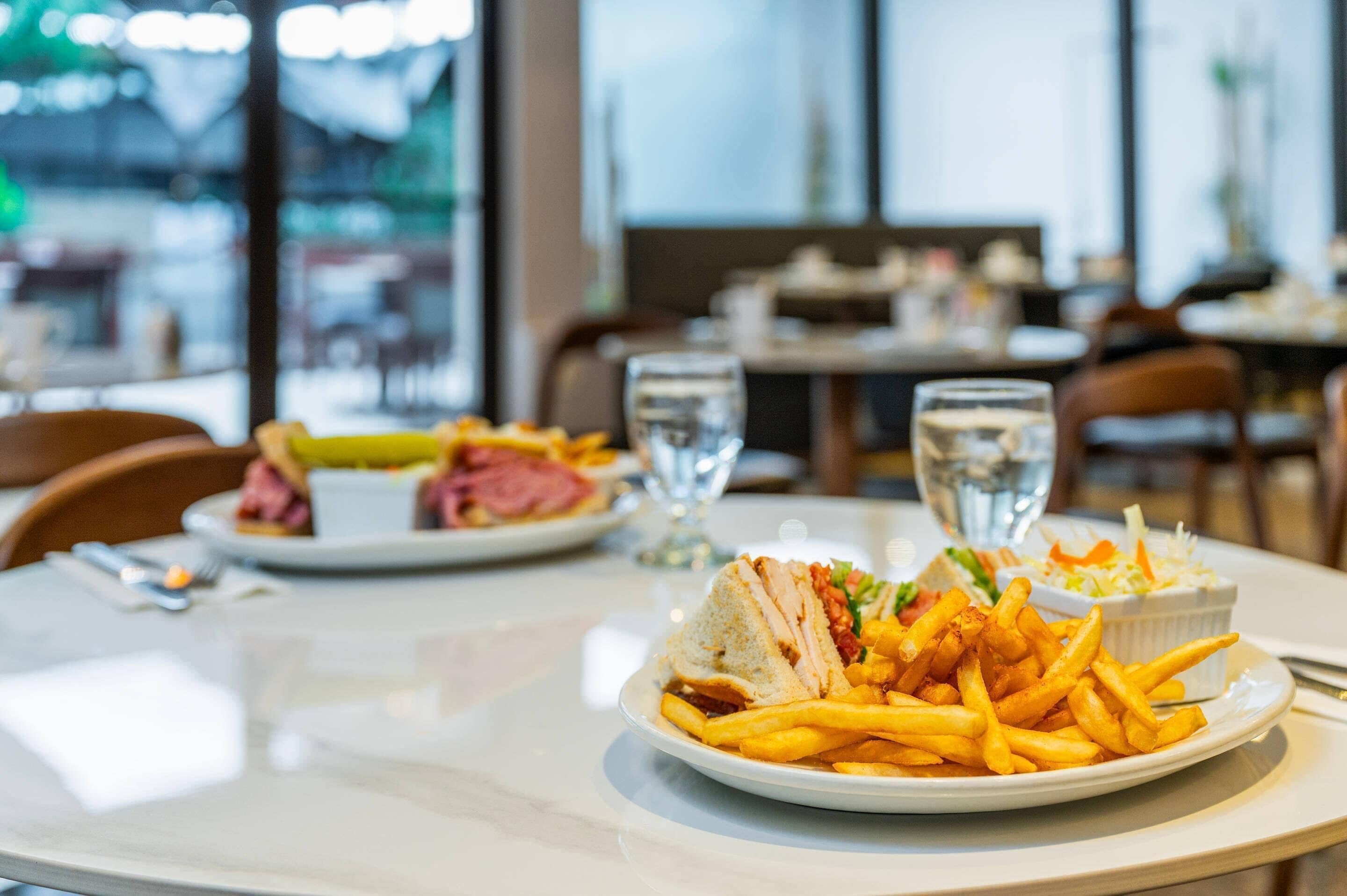A dining table with plates of food, glasses of water, and a view of the street outside.