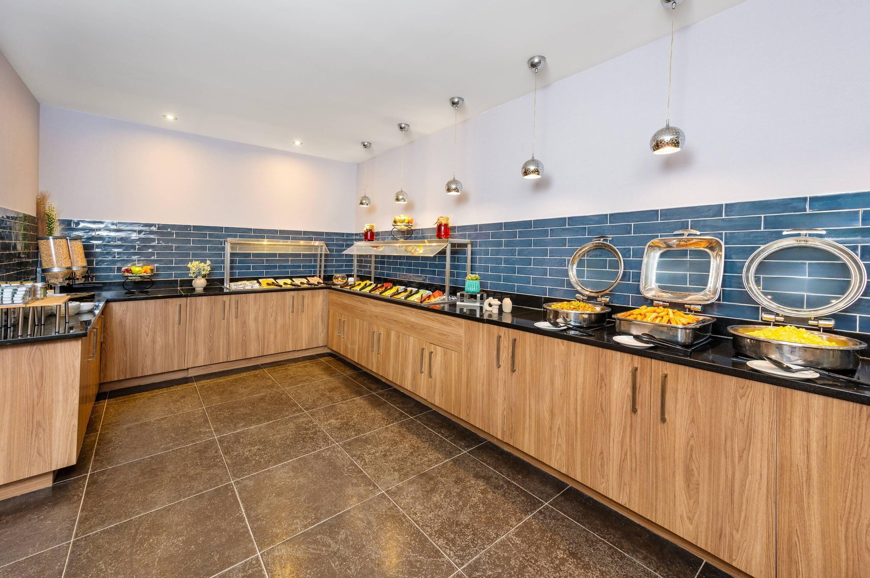 Una cocina moderna con armarios de madera, encimera negra y salpicadero de azulejos azules.