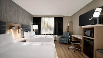 Une chambre d’hôtel avec deux lits, un bureau, une chaise, une télévision et un four à micro-ondes.