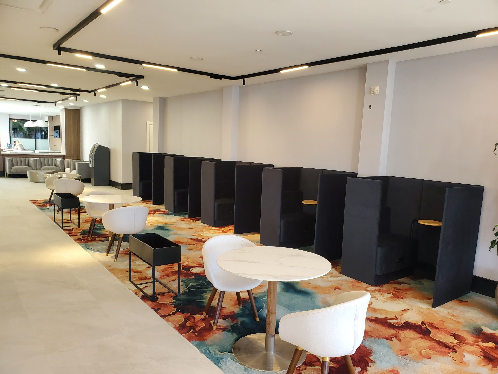Un espace de détente moderne, avec des sièges confortables, un tapis à motifs et un coin cuisine en arrière-plan.