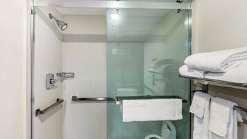 Un baño moderno con ducha de vidrio, un perchero con toallas dobladas y una puerta de cristal.